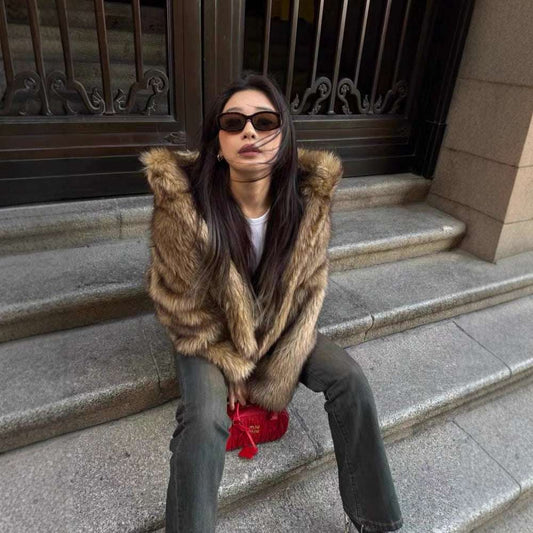 Woman in fur coat and sunglasses sitting on steps holding a red bag.
