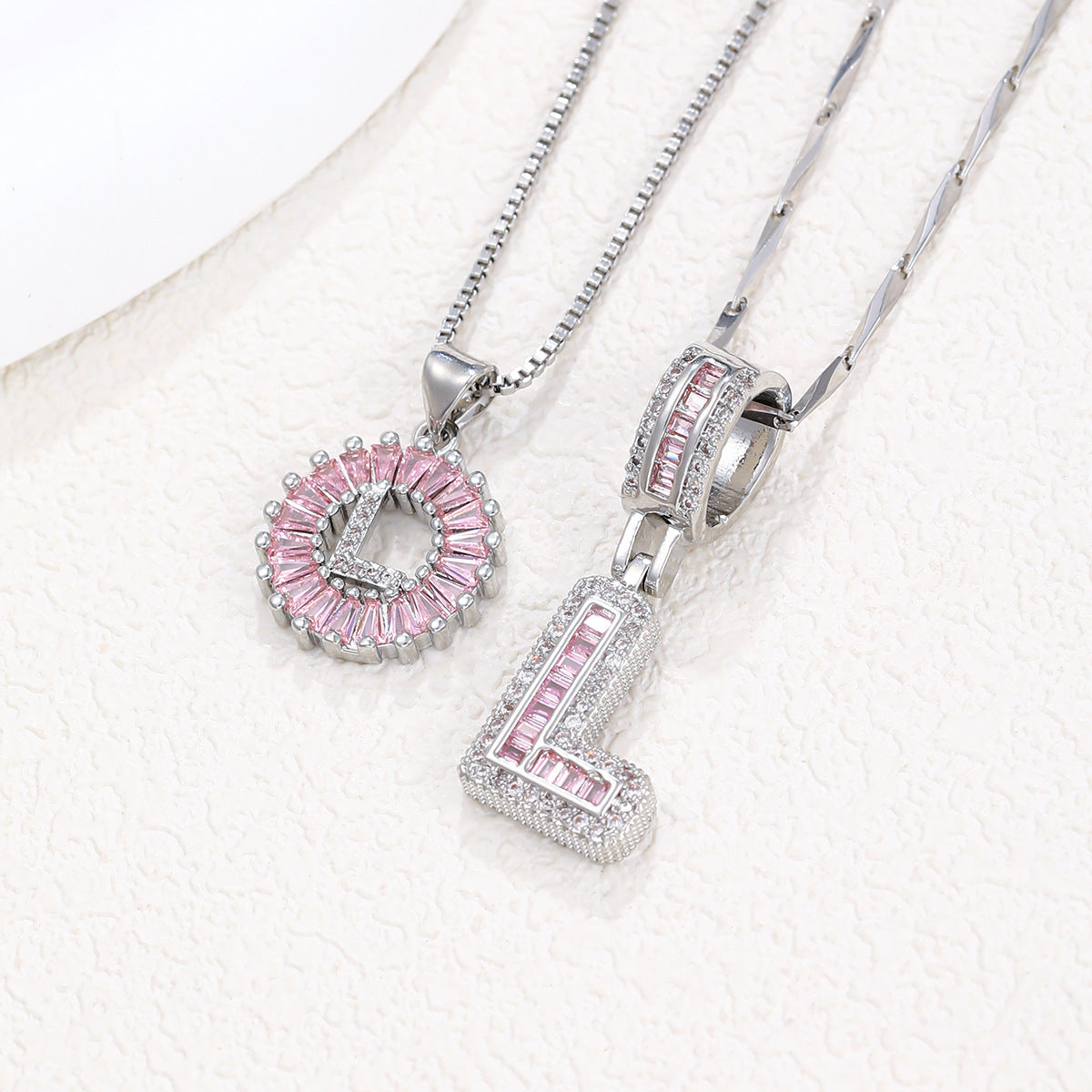 Silver pendant necklace set with pink crystal flower charm and letter charm, layered on two chains