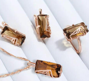 Gold-tone rectangular gemstone necklace pendant with matching rings set on white