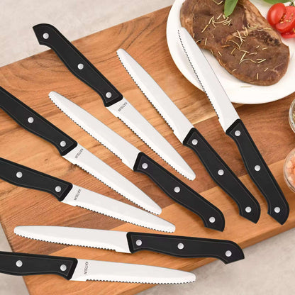 Serrated steak knives with black handles and white blades, arranged on a wooden board