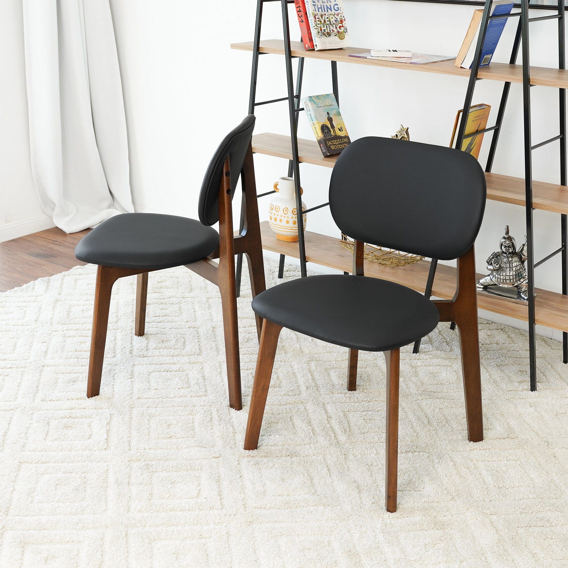 Set of 2 black leather dining chairs with curved backs and seats on wood legs