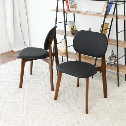 Set of 2 black leather dining chairs with curved backs and seats on wood legs