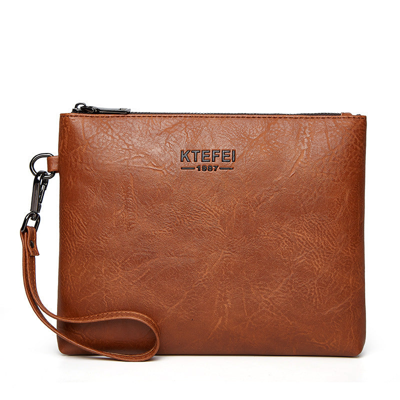 Men's cognac clutch bag with zip top, logo, and wrist strap, textured finish