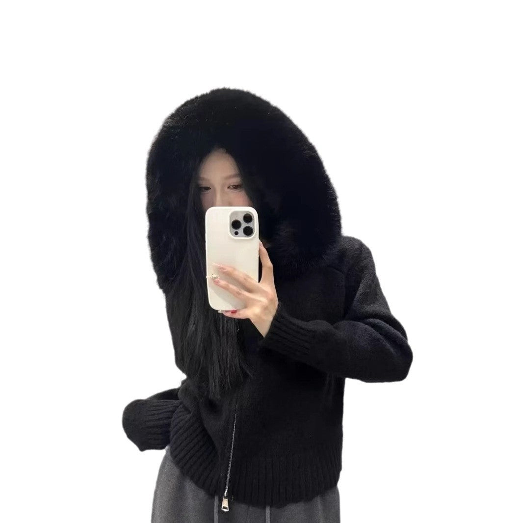 Person wearing a black hoodie with fur trim, holding a phone on a white background