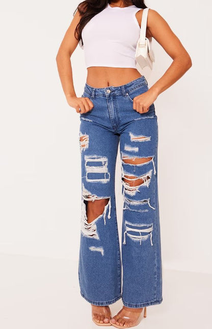 Light blue distressed denim jeans with large rips and frayed wide-leg hems