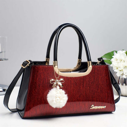 Structured glitter tote handbag in red with black handles and white pom-pom charm