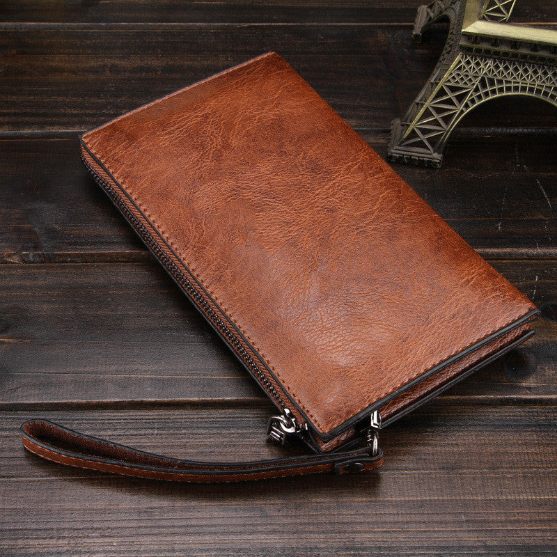 Reddish-brown leather zip wallet with stitched edges and wrist strap