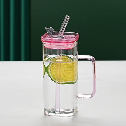 Square glass drinking cup with pink lid, clear body, straw, and side handle.