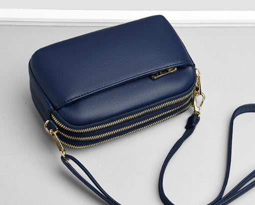 Blue crossbody bag with gold zipper and adjustable shoulder strap.