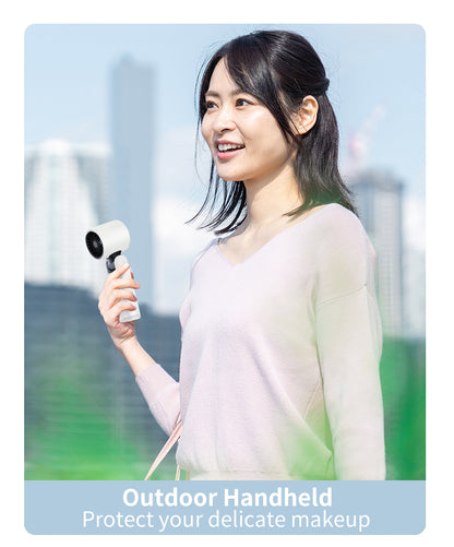 Handheld mini fan in white with circular front grille, held near a person’s face