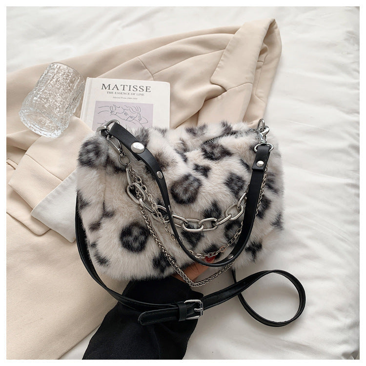 Grey plush leopard print crossbody bag with silver chain links and black leather straps
