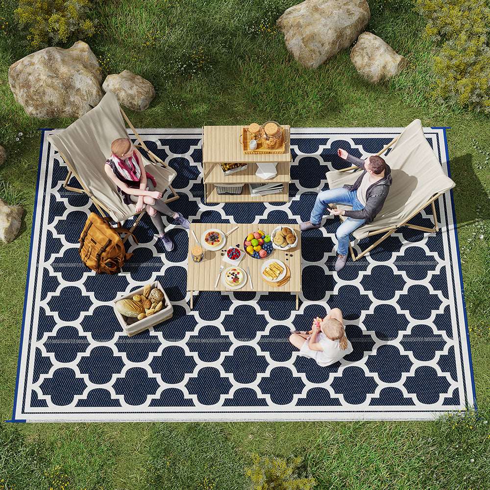 Reversible outdoor rug with navy-and-white quatrefoil pattern and bordered edges