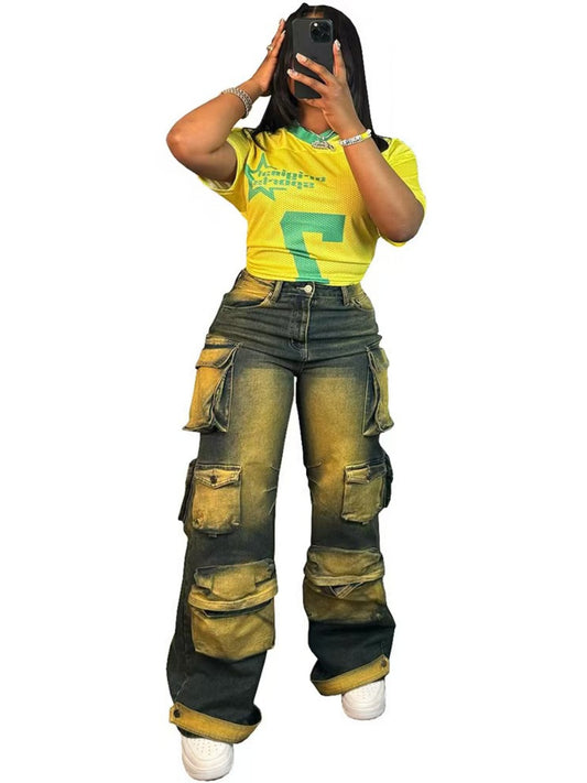 A stylish woman wearing baggy vintage-wash denim workwear pants featuring oversized utility pockets and a relaxed wide-leg silhouette.