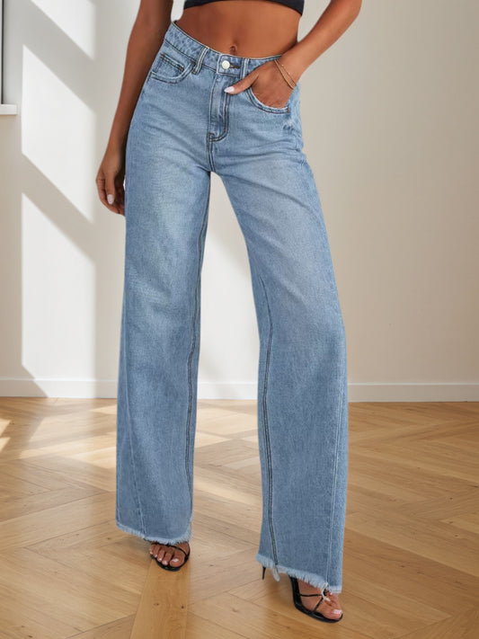 A woman modeling dark-wash wide-leg denim pants with a structured waist and a relaxed, flowing leg silhouette.