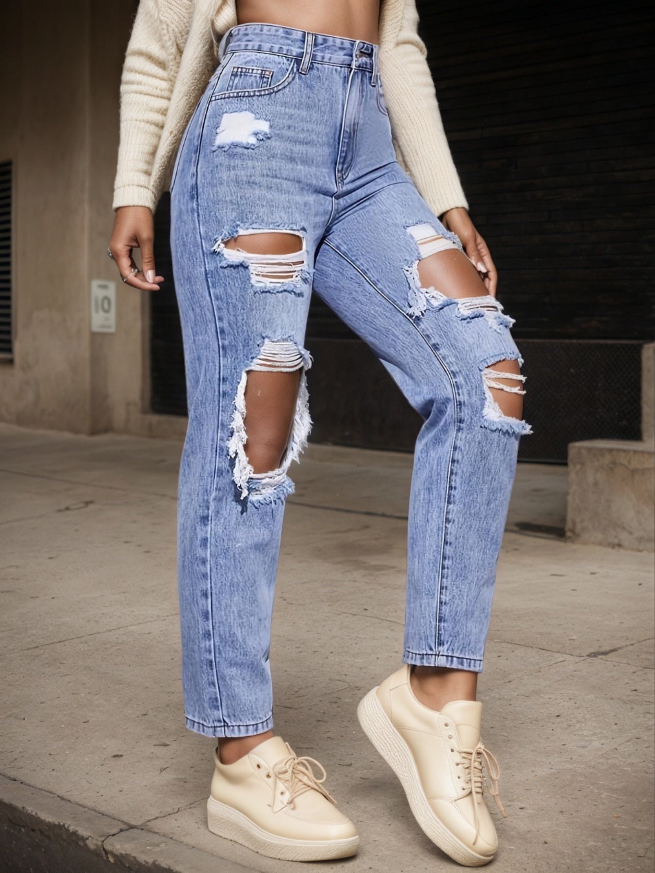 A woman modeling light-wash straight-leg denim with high-waisted construction and intentional distressed rips at the knees and pockets for a streetwear look.