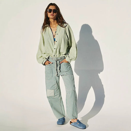 A woman wearing loose, wide-leg commuter trousers featuring vertical striped stitching and a practical drawstring waist, styled for a professional yet relaxed office look.