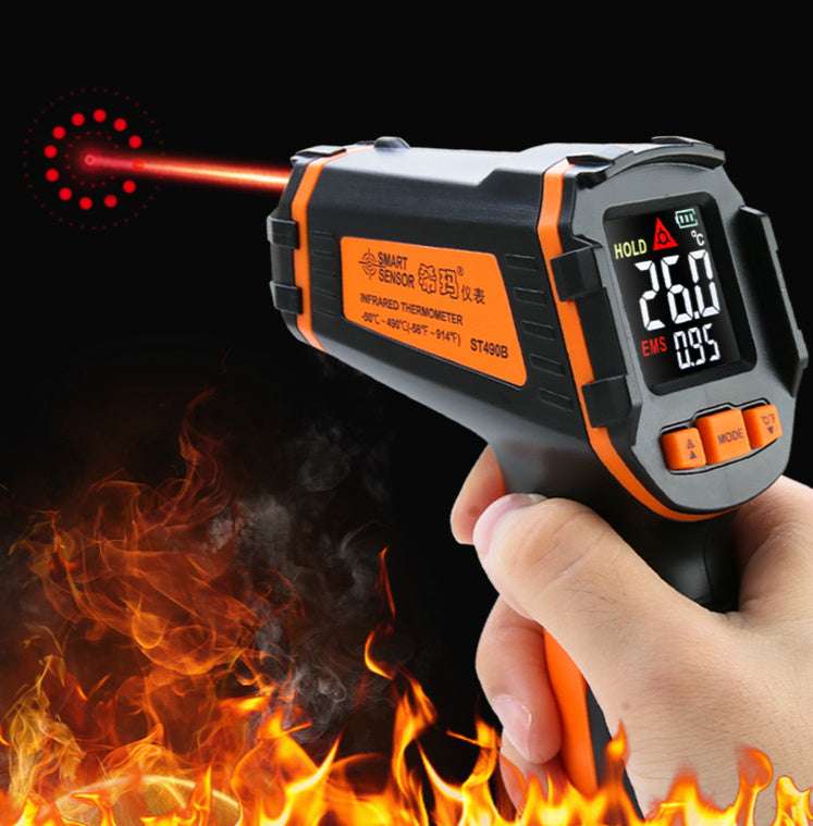 Infrared thermometer held by a hand with flames and smoke in the background