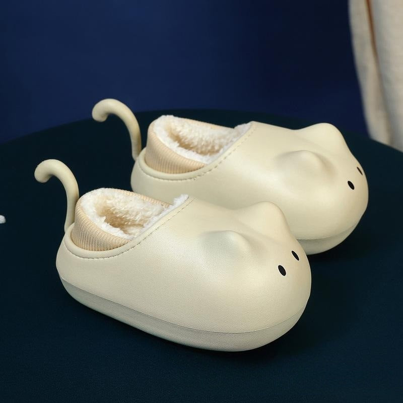 A pair of beige children's cotton slippers with a cartoon pattern, featuring non-slip soles and fleece lining.