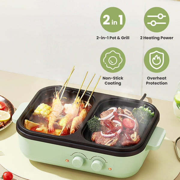 Compact black 2-in-1 electric cooker featuring a round hot pot on one side and a ribbed grill surface on the other, steaming with fresh vegetables and meat inside a home kitchen