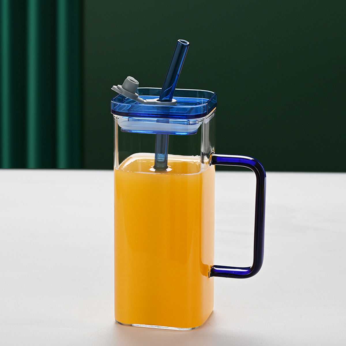 Clear square glass cup with blue lid, blue handle, and blue straw