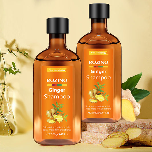 Two bottles of Rozino Ginger Shampoo on a beige background with ginger slices and leaves.