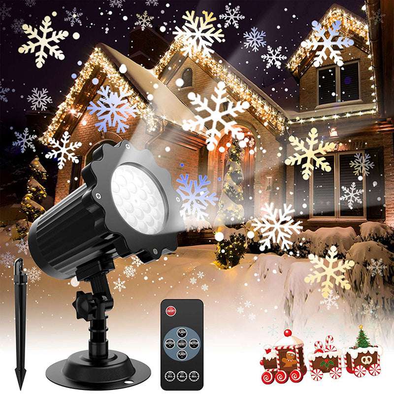 Outdoor Christmas light projector with snowflake patterns on a house at night.