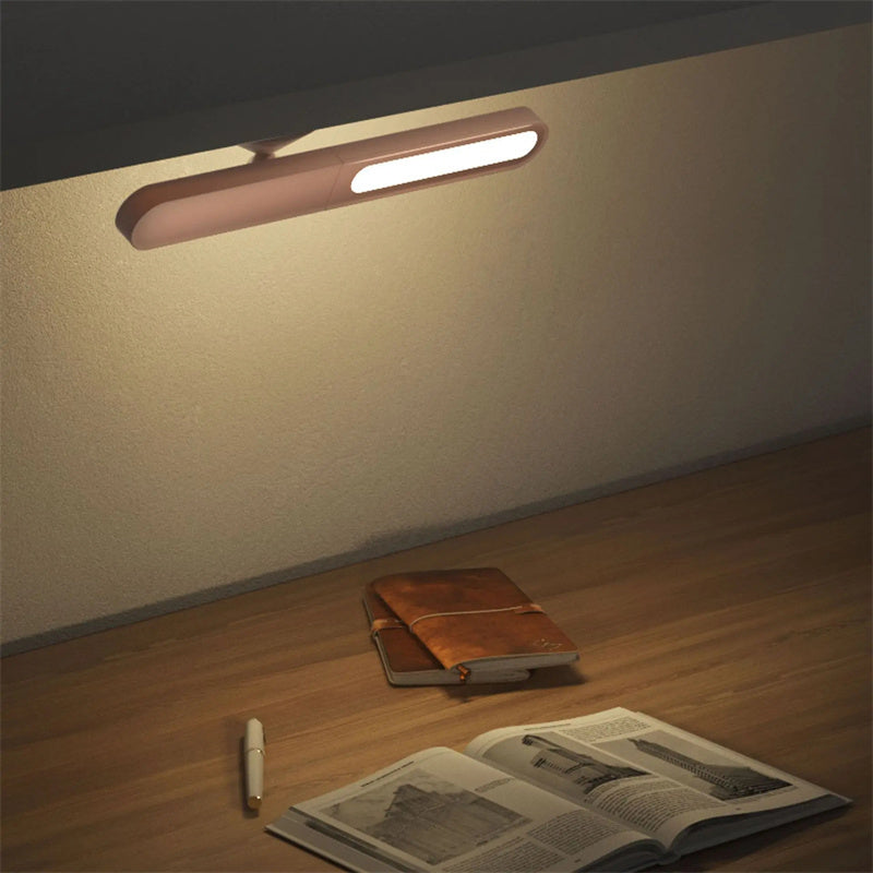 Wall-mounted light fixture illuminating a wooden floor with a book and pen.