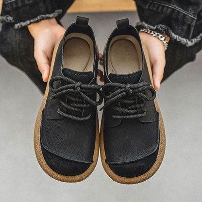 Black and brown shoes held by a person on a neutral background