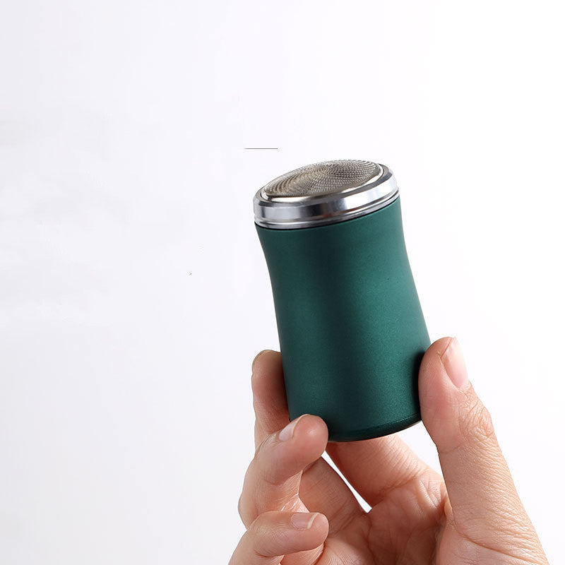 Hand holding a green and silver cylindrical object against a white background