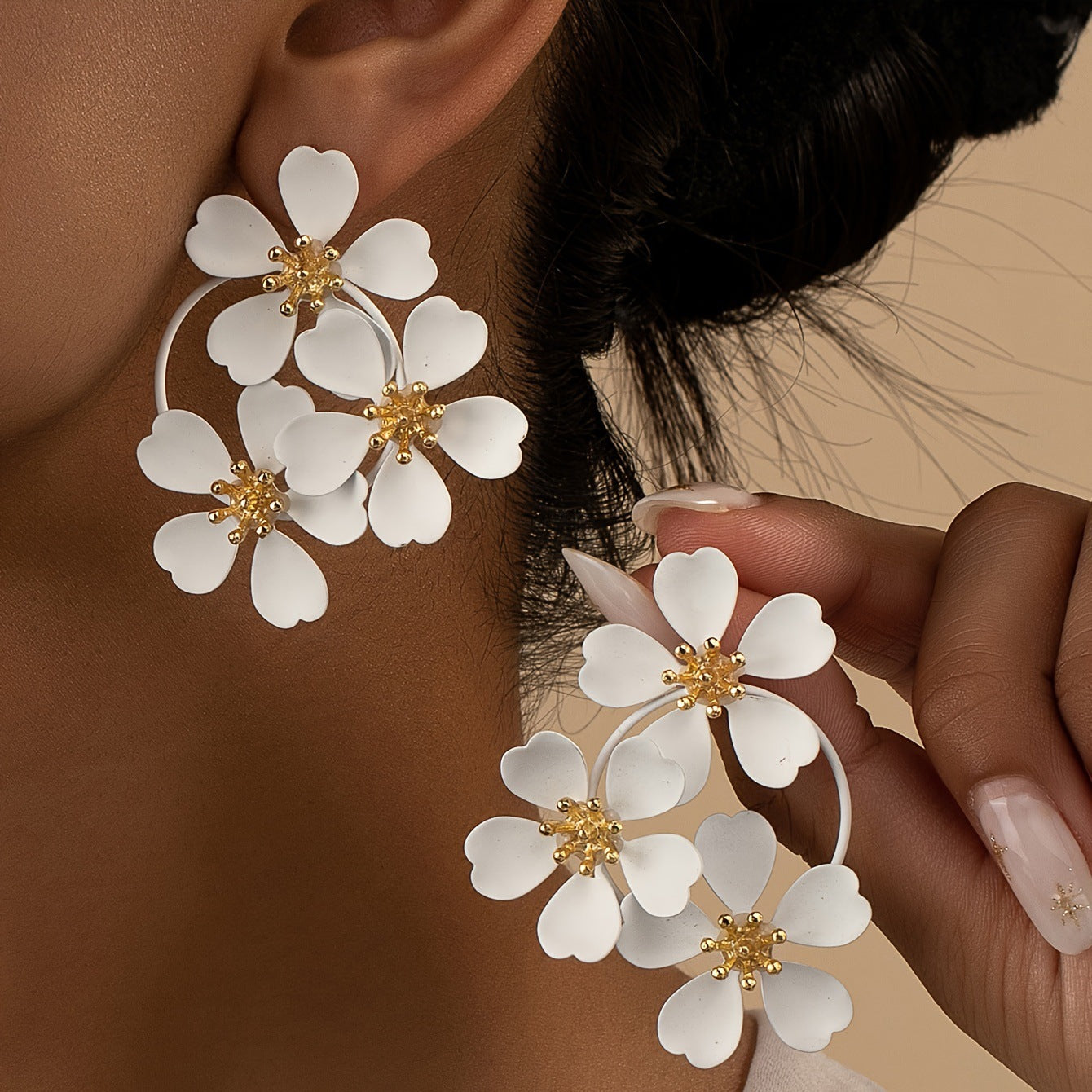 White flower hoop earrings worn on ear, with gold-tone centers and three blossoms.