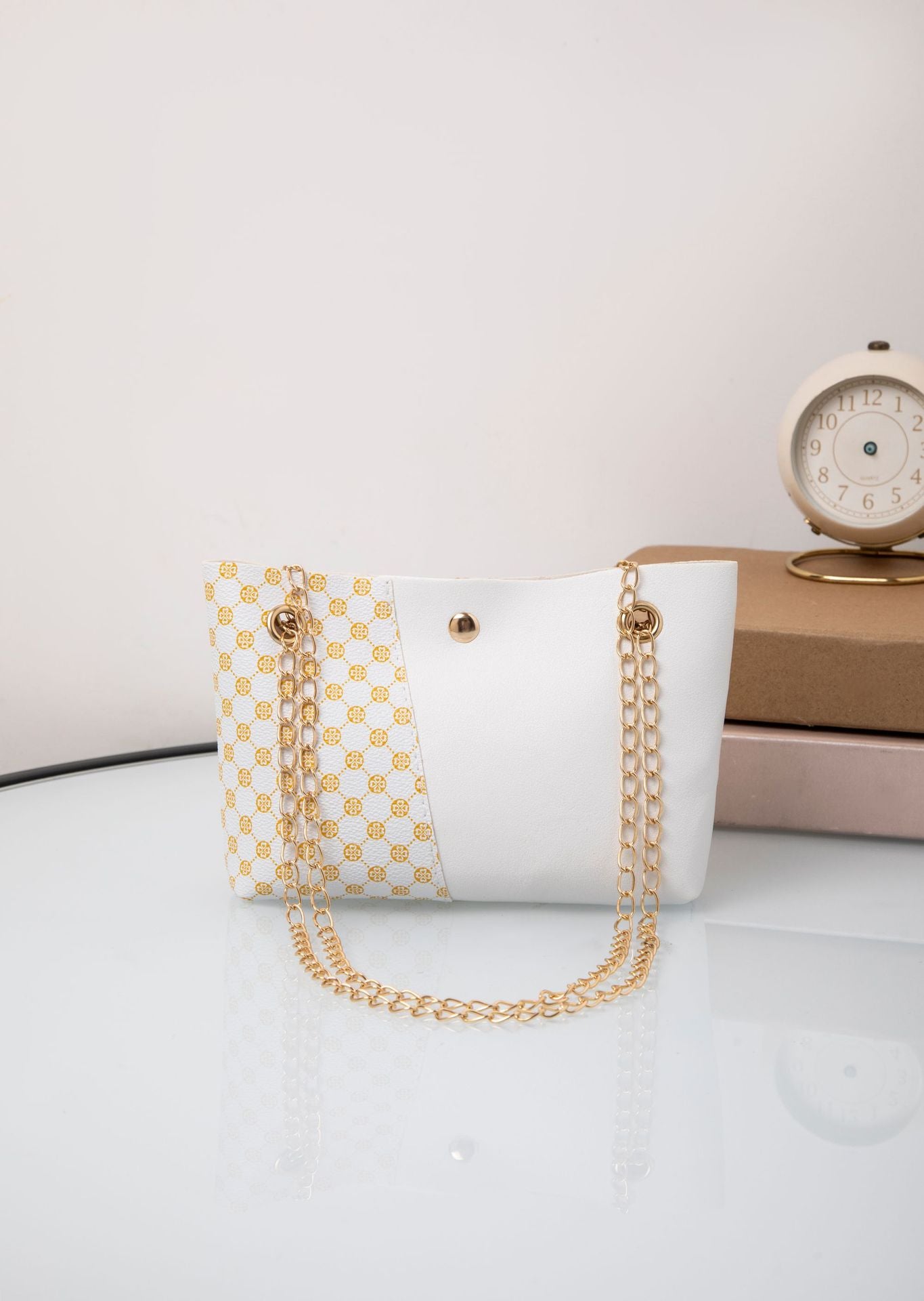White and tan patterned shoulder bag with gold chain strap and round snap button