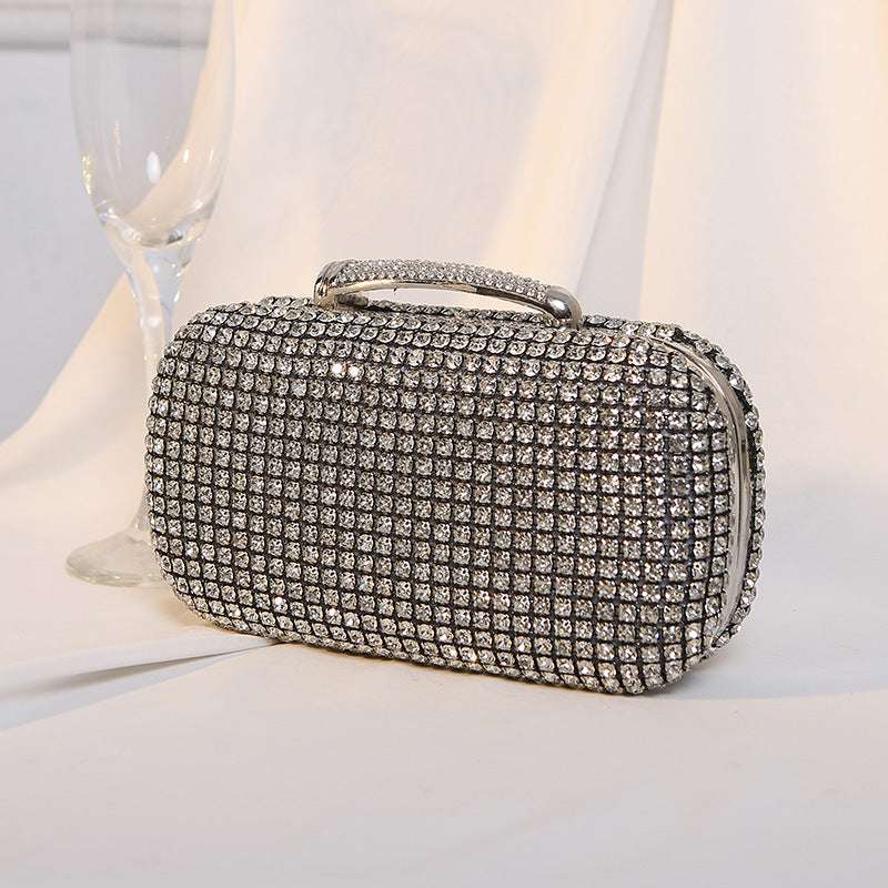 Silver rhinestone clutch bag with gold-tone top handle and curved clasp front