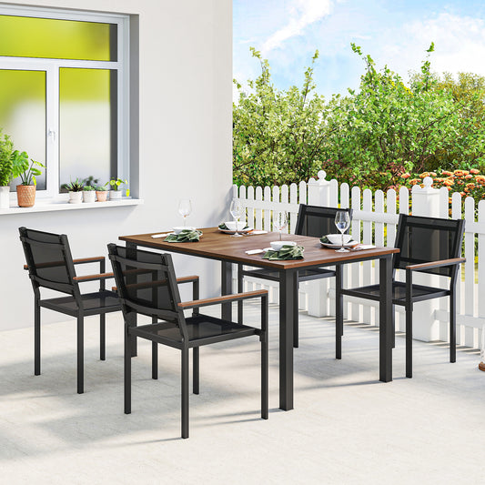 Outdoor dining set for 4 with a long rectangle acacia wood table and four black stackable chairs on a garden patio
