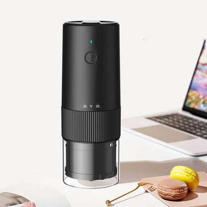 Black coffee grinder on a desk with a laptop and snacks