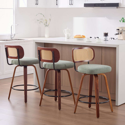 Set of three 26-inch counter height bar stools featuring walnut frames, woven cane rattan backs, and light green linen upholstered swivel seats.