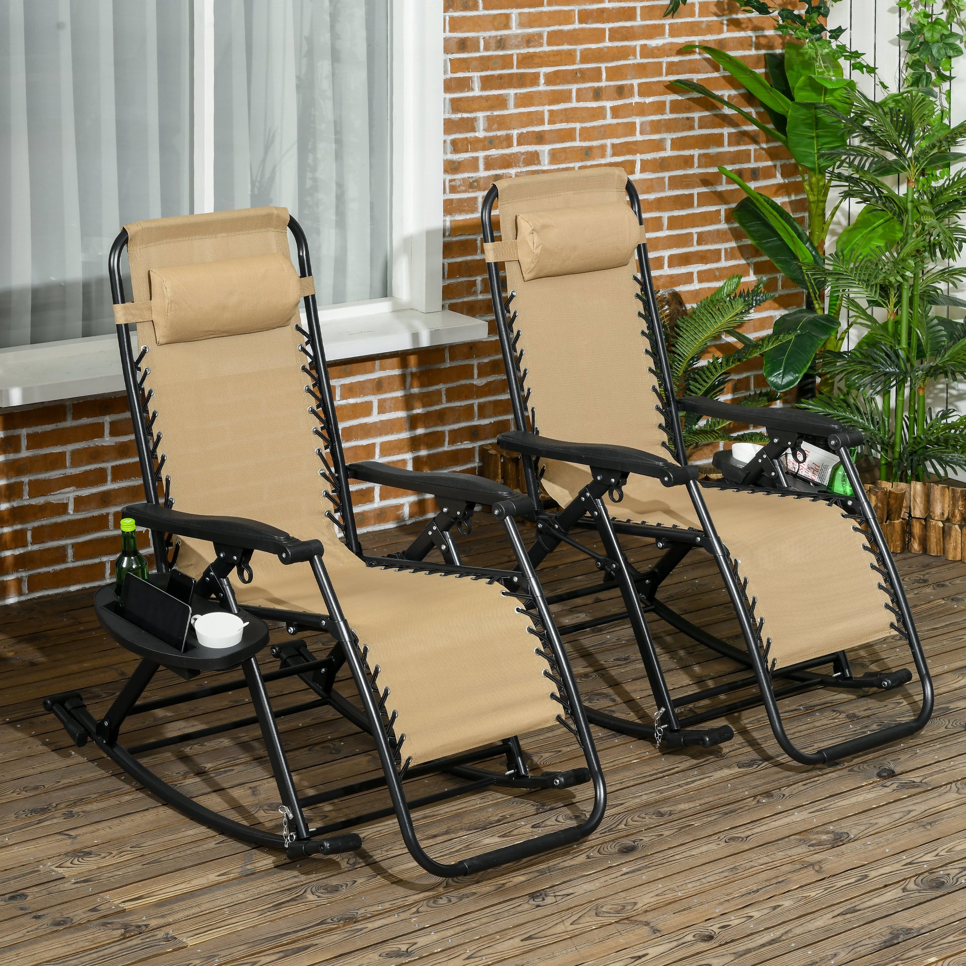 Two beige foldable zero gravity rocking chairs for outdoor lounging, featuring a reclining metal frame, padded headrest pillows, and a side tray with cup and phone holders.