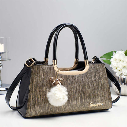 Structured glitter tote handbag with black handles and white pom-pom charm
