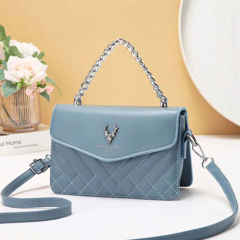 Quilted mini crossbody bag in light blue with silver chain strap and front flap with snap.