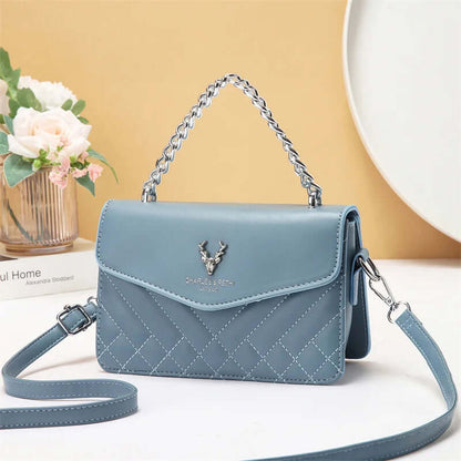 Quilted mini crossbody bag in light blue with silver chain strap and front flap with snap.