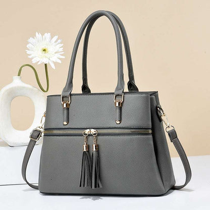 A large capacity soft leather shoulder bag with a tassel design, displayed in a horizontal square shape. The bag has a combination of colors including black and red, with a visible zipper and a tassel hanging from the main compartment.