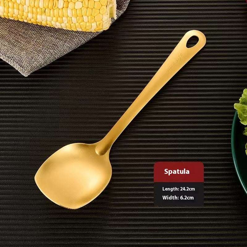 Gold spatula on a dark surface with text indicating its dimensions.