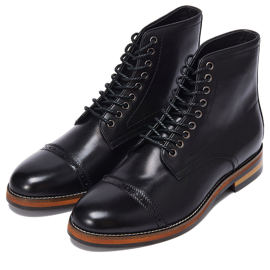 Pair of black leather boots with brown soles on a white background