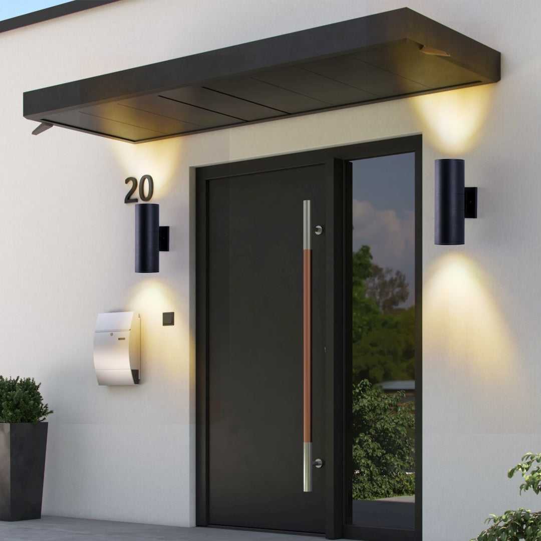 Matte black outdoor up-down wall lights, cylindrical heads with warm light glow.