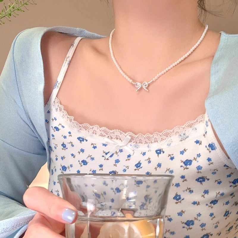White pearl choker necklace with butterfly-style centerpiece on a slim chain