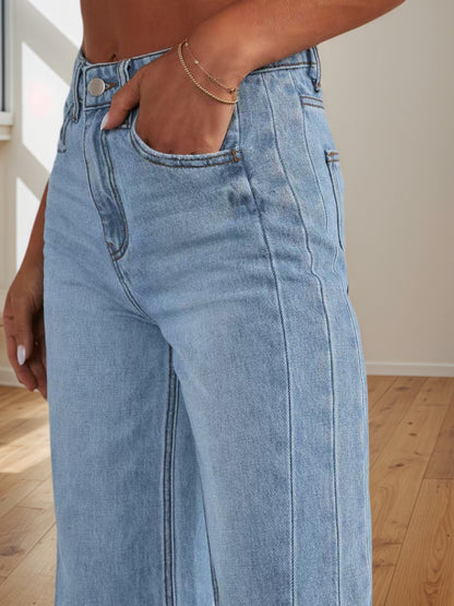 Women's light blue denim pants close-up: front pocket, button waistband, belt loops.