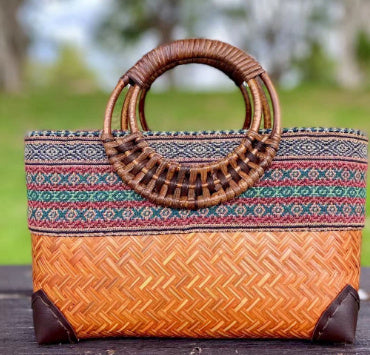 Woven bamboo handbag with brown handle, multicolor patterned top, orange woven body