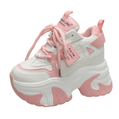 A pair of pink and white athletic shoes with a low-top design and mid heel height, displayed alongside a model wearing the shoes.
