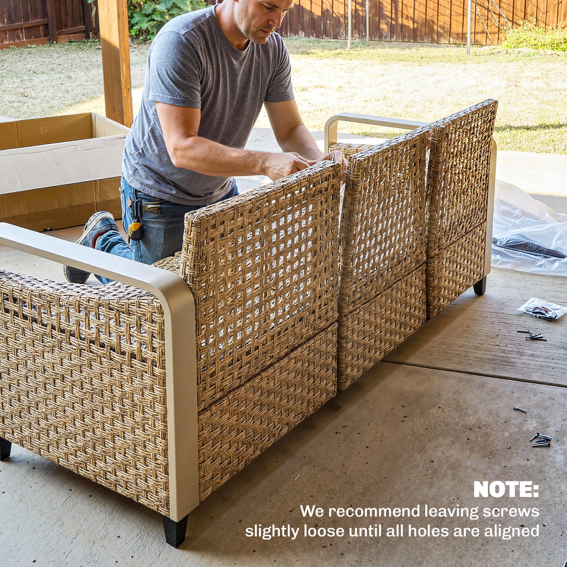 3-seat rattan outdoor sofa with gray cushions, being assembled by a man