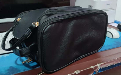 Black leather-look cosmetic bag with double zippers and a crossbody strap