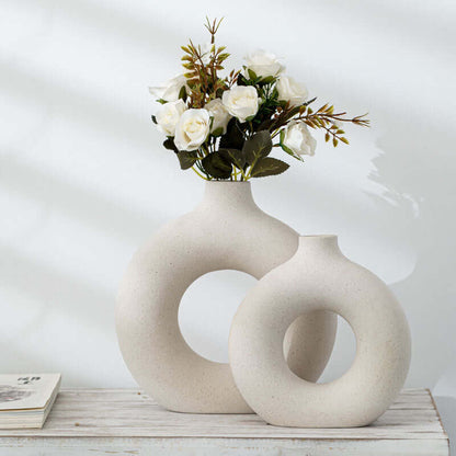 Off-white ceramic vase with circular cutout, holding a small floral arrangement
